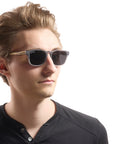 A person wearing Johnny Fly "Splinter" sunglasses featuring a sleek combination of an acetate front section, wooden arms, and nylon polarized lenses.